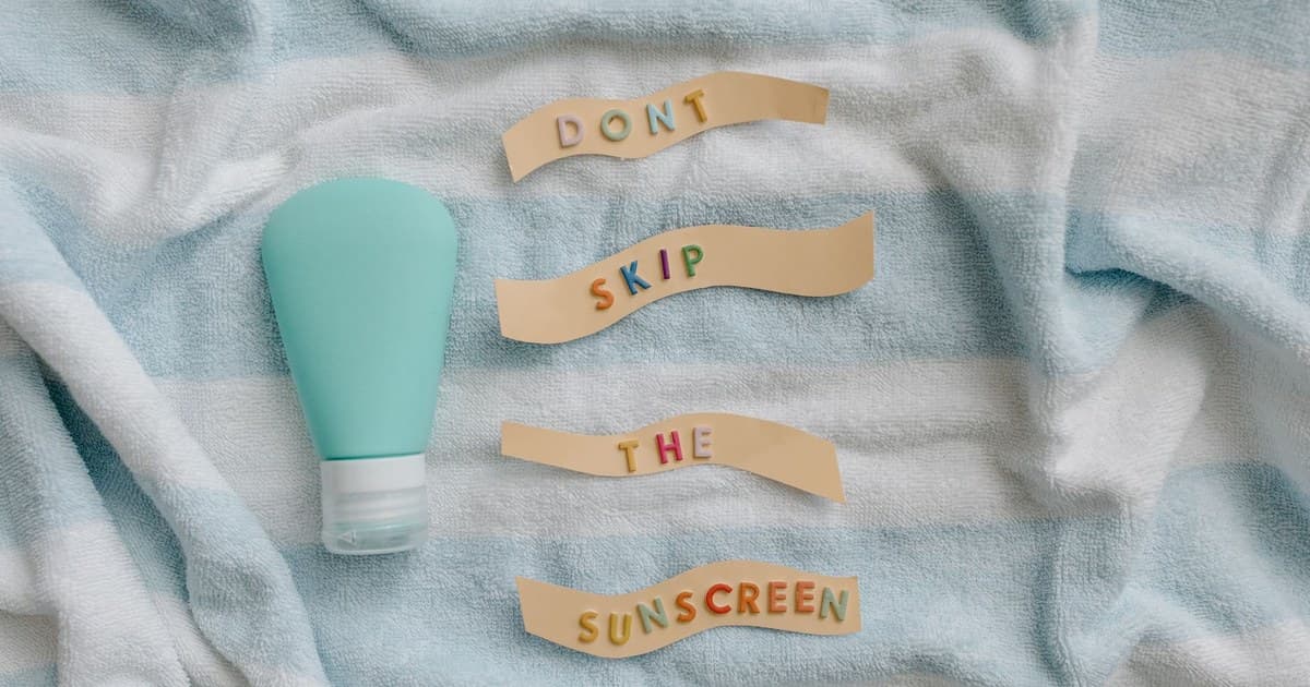 수건 위에 놓인 선크림 용기와 'DON'T SKIP THE SUNSCREEN' 글자 조각